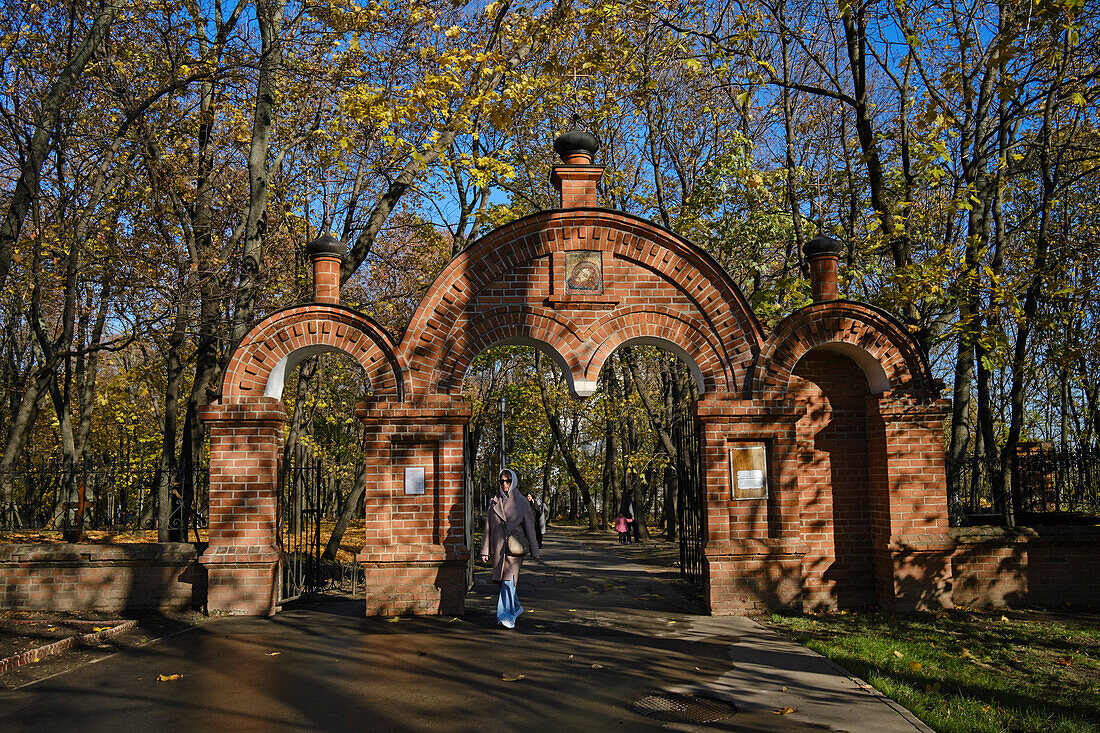 Woman walks through a church gate in Kolomenskoye Museum Reserve on a sunny autumn day. Moscow, Russia.