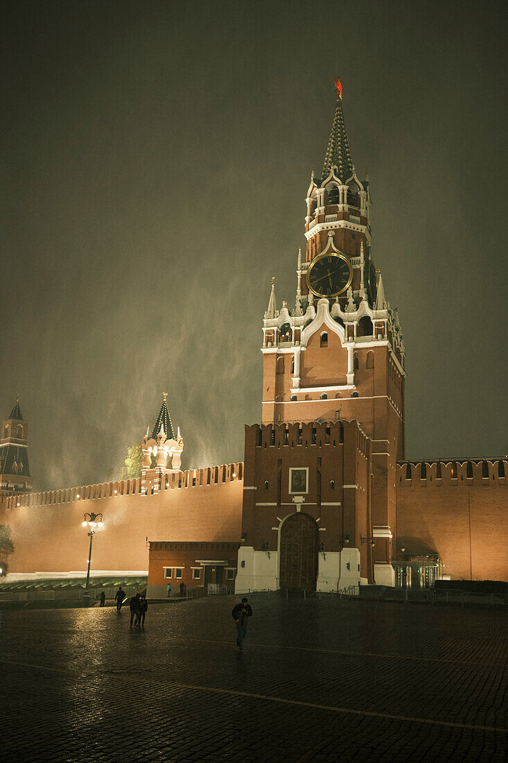 View of the Spasskaya Tower and the Kremlin Wall during a sudden snowstorm at night. Moscow, Russia.