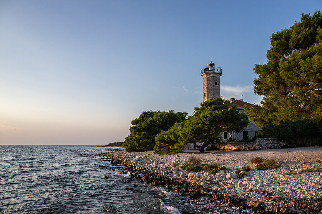  Island of Vir, lighthouse and pine forest with view over the coast to the building and sunset, Dalmatia, Croatia, Adriatic Sea, Mediterranean Sea 