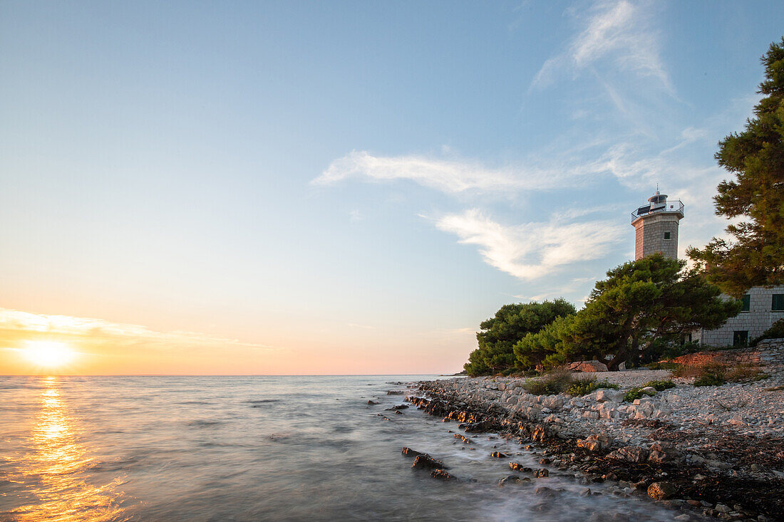  Island of Vir, lighthouse and pine forest with view over the coast to the building and sunset, Dalmatia, Croatia, Adriatic Sea, Mediterranean Sea 