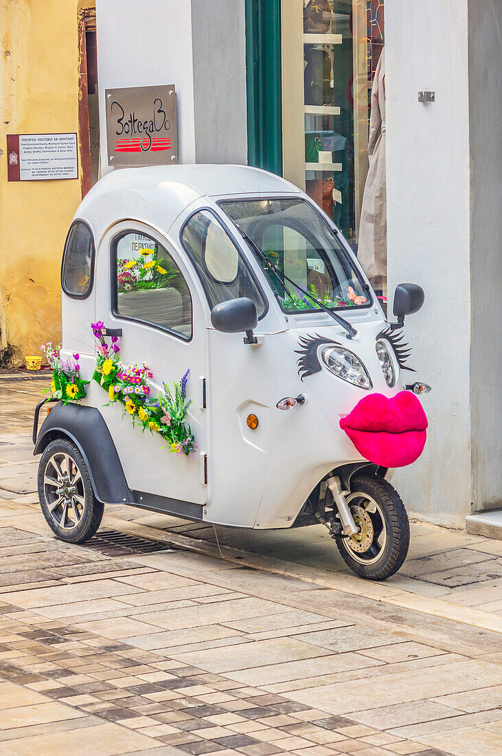 Motorisiertes Dreirad mit Girlanden und Mund vor Weinhandlung, in der Stadt  Nafplio, Peloponnes, Argolischer Golf, Ägäis, Griechenland