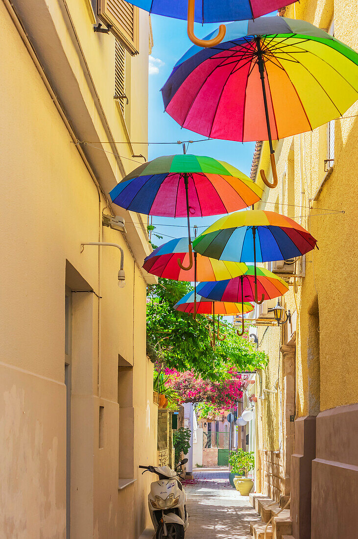  Aegina is a Greek island in the Saronic Gulf in the western Aegean Sea, also called the Gulf of Aegina. The island is located 25 km southwest of Athens. Here a street with colorful umbrellas 