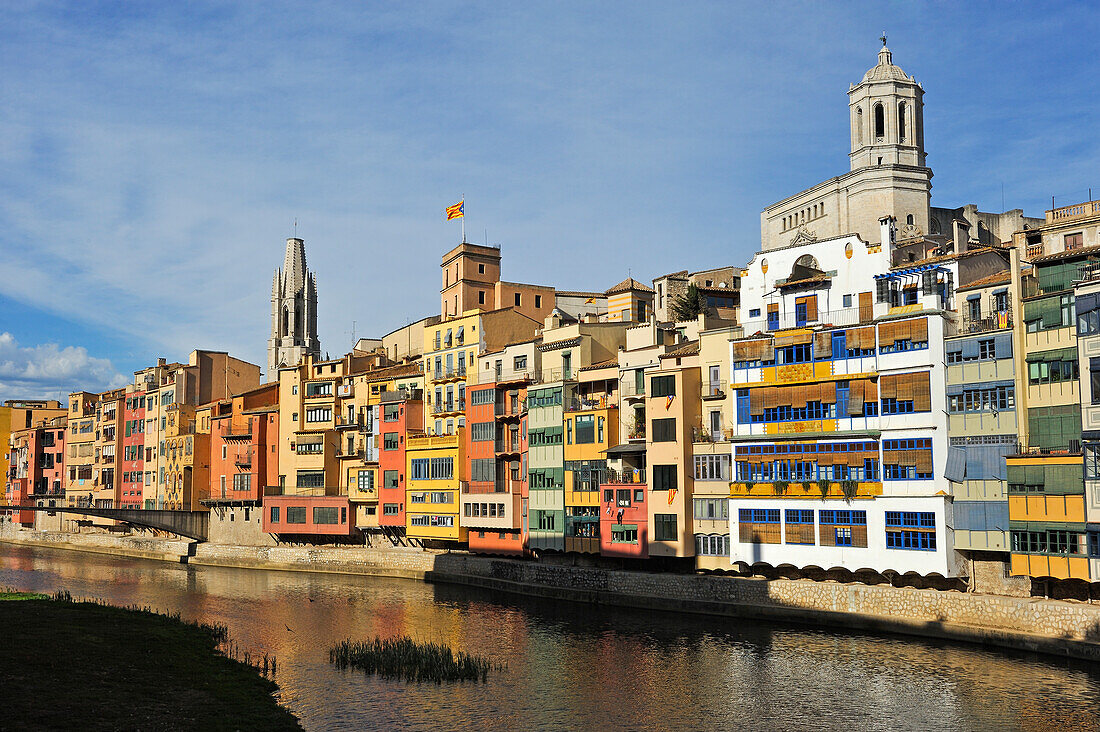 front of the houses, among which the white Casa Maso, birthplace of the Catalan architect Rafael Masó (1880-1935), by the Onyar River, with the tower bell of the Cathedral and the Collegiate Church of San Felix in the background, Girona, Catalonia, Spain,Europe