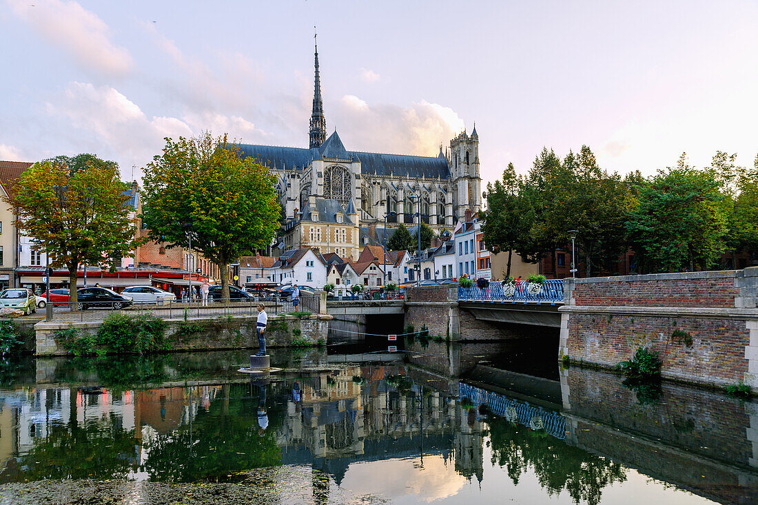  Notre-Dame Cathedral and houses on Place du Don from Quai Bélu (Belu) on the Somme with wooden sculpture &quot;L&#39;homme sur sa bouée&quot; (1993) by Stephan Balkenhol in the Saint-Leu district of Amiens in the Somme department in the Hauts-de-France region of France 