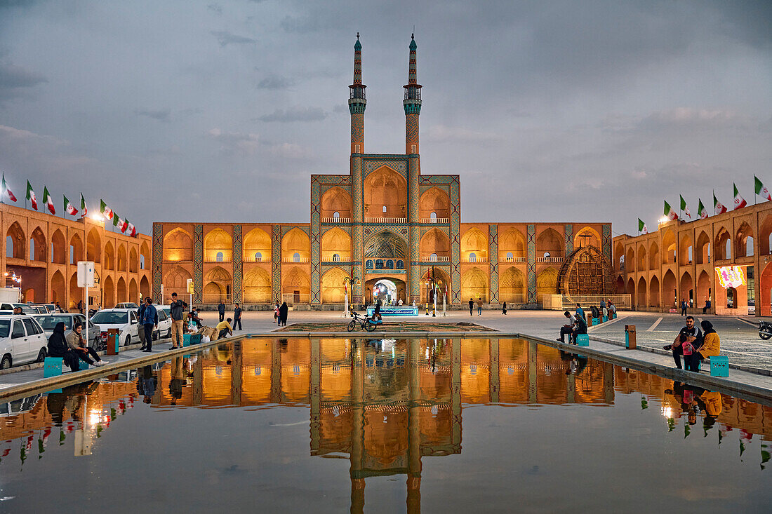 View of Amir Chakhmaq Complex and adjacent water pool illuminated at dusk. Yazd, Iran.