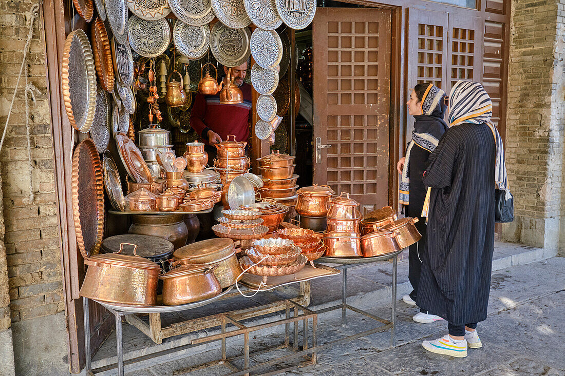  Zwei iranische Frauen kaufen Kupferkochgeschirr in einem kleinen Laden auf dem Naqsh-e Jahan-Platz, einem UNESCO-Weltkulturerbe. Isfahan, Iran. 