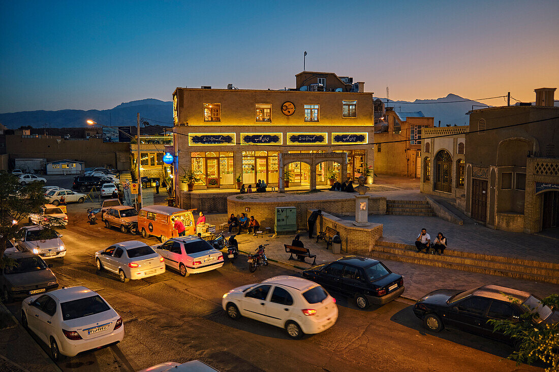  Luftaufnahme der Alavi-Straße mit fahrenden Autos und umliegenden, nachts beleuchteten Gebäuden. Kashan, Iran. 