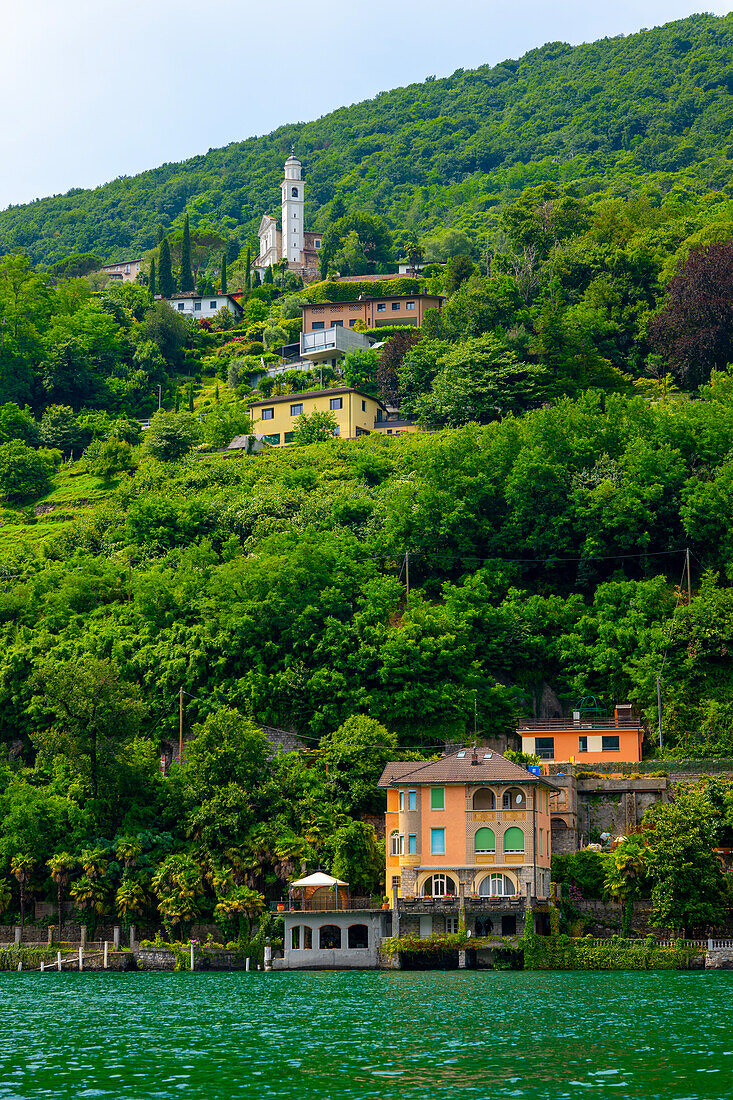 Haus und Kirche auf einem Berg an einem sonnigen Sommertag am Ufer, Luganersee in Vico Morcote, Lugano, Tessin, Schweiz.