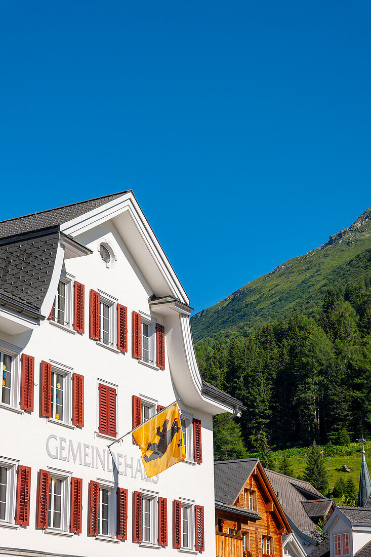 Altstadt mit Gemeindehaus und Berg an einem sonnigen Sommertag in Andermatt, Uri, Schweiz.