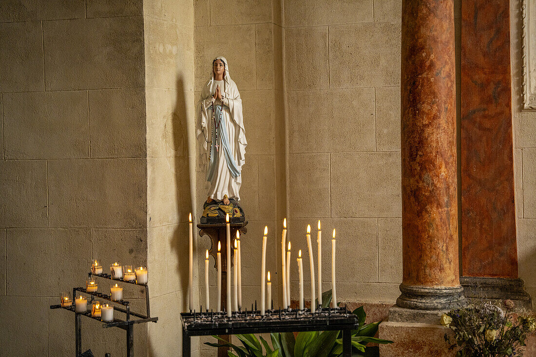 Marienfigur und Kerzen in der Kirche in der Altstadt von Roussillon, Département Vaucluse, Provence-Alpes-Côte d’Azur, Frankreich