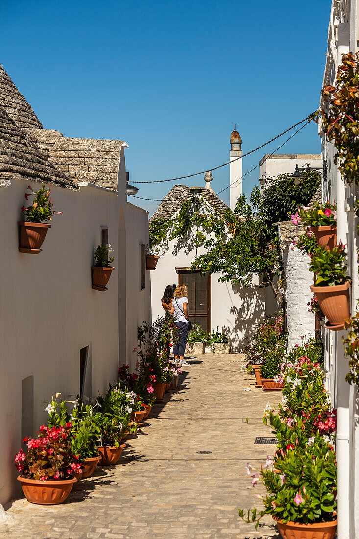 Touristen in einer Gasse, Trulli-Häuser in Alberobello, Apulien, Italien.