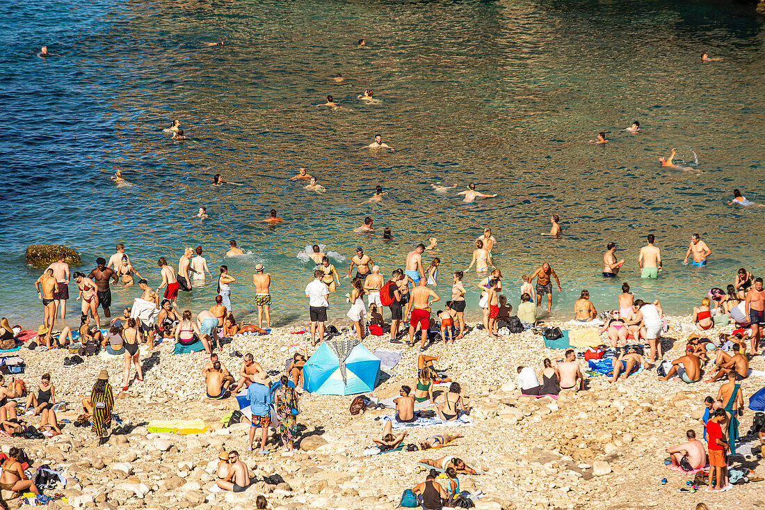 Closeup of people enjoying the beach of  Cala Monachile or Lama Monachile in Polignano a Mare, Puglia, Italy.