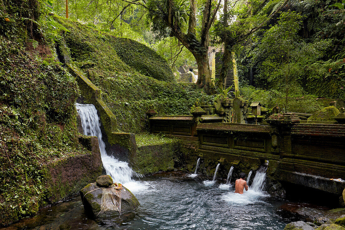 Indonesian man takes a bath in the men's half of the bathing pool in the Mengening Temple. Tampaksiring, Bali, Indonesia.