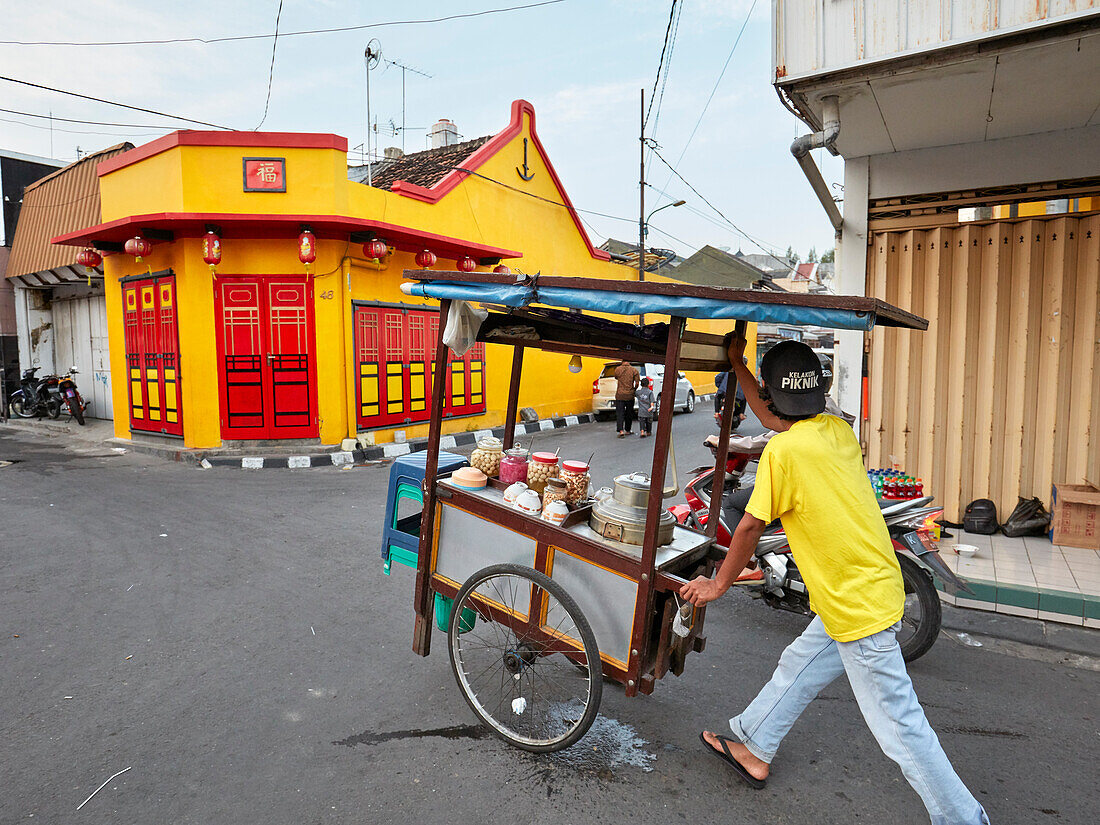 Street vendor pushes his mobile food stall up the Ketandan Wetan street. Yogyakarta, Java, Indonesia.