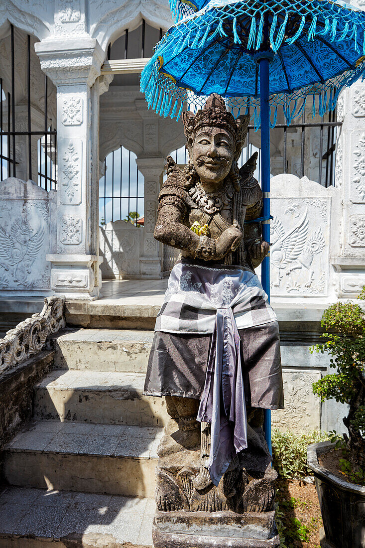  Aus Stein geschnitzte Statue im Sarong gekleidet im Ujung-Wasserpalast (Taman Ujung). Regentschaft Karangasem, Bali, Indonesien. 