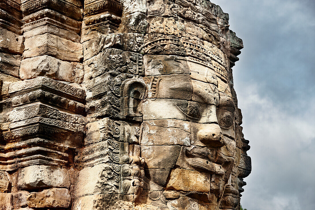 Giant carved stone face in the ancient Bayon temple. Angkor Archaeological Park, Siem Reap Province, Cambodia.