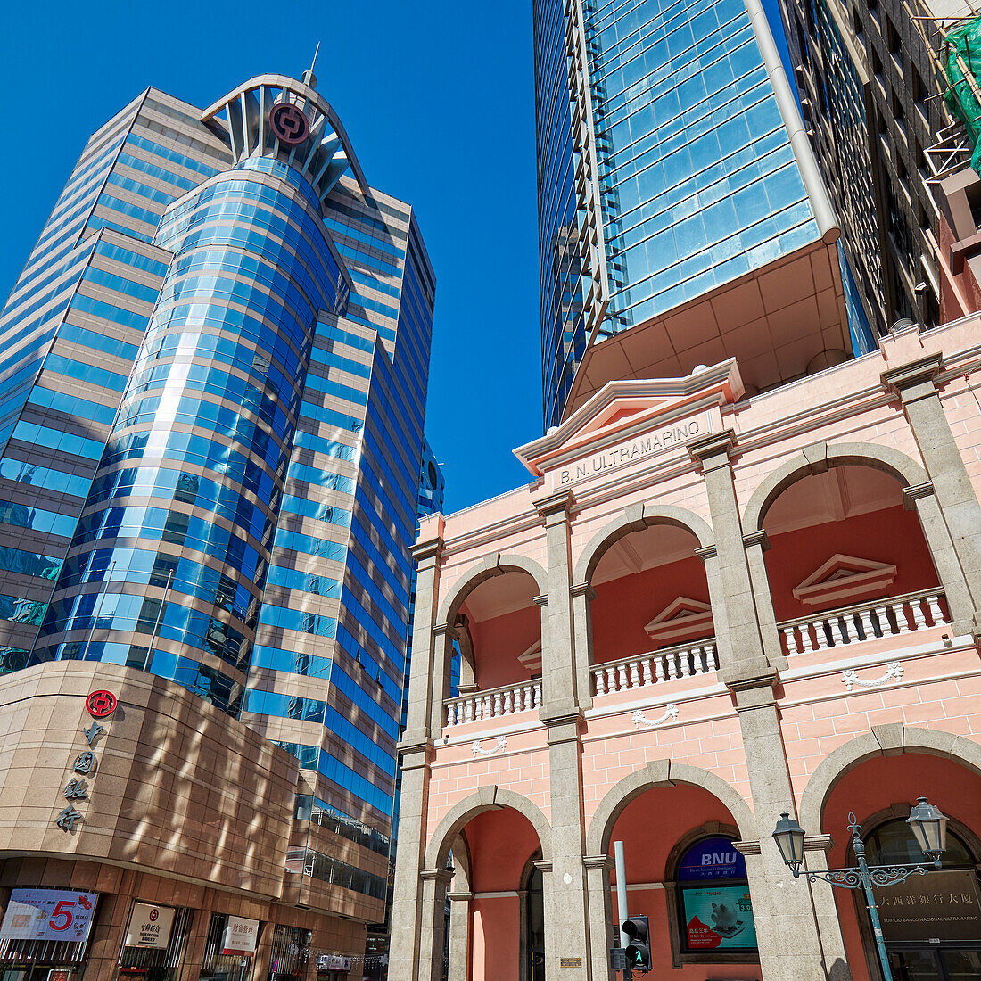 A view from below of the building of the Banco Nacional Ultramarino (BNU) and nearby high-rise buildings. Macau, China.