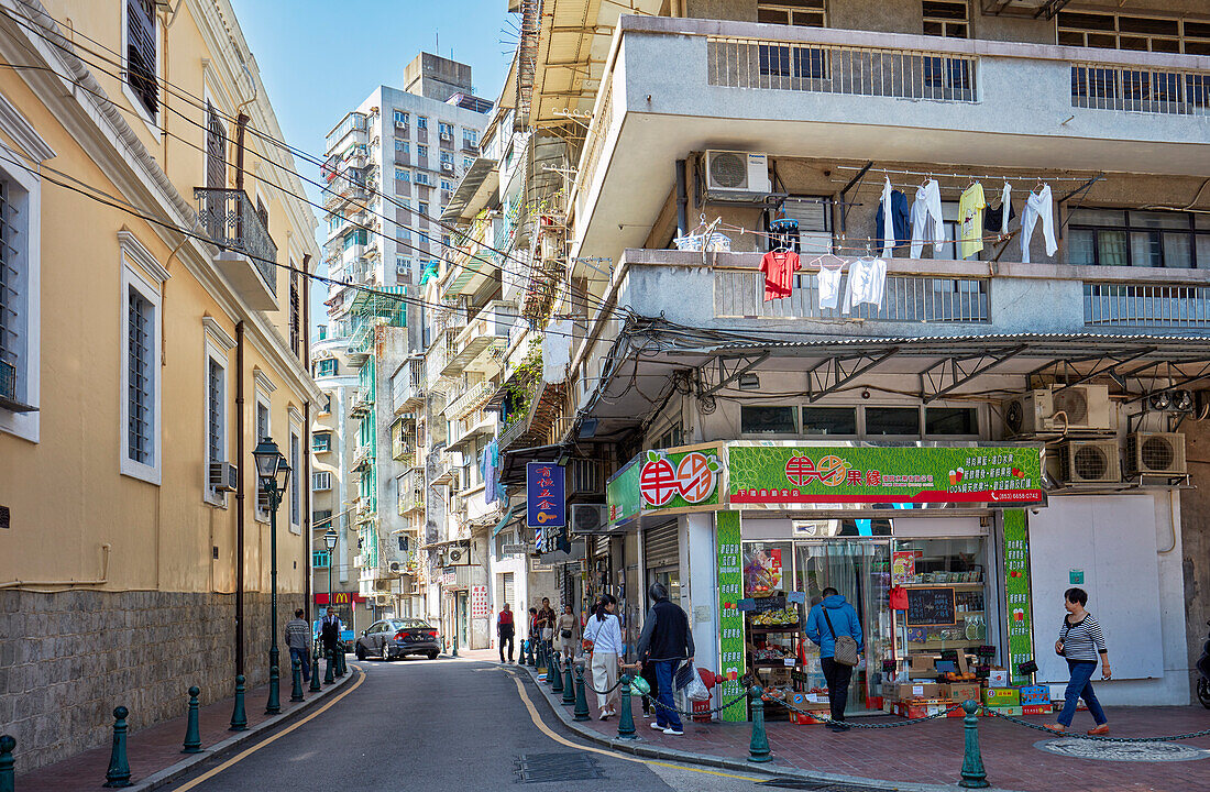 People walk along a narrow street in the historic centre of Macau city, China.