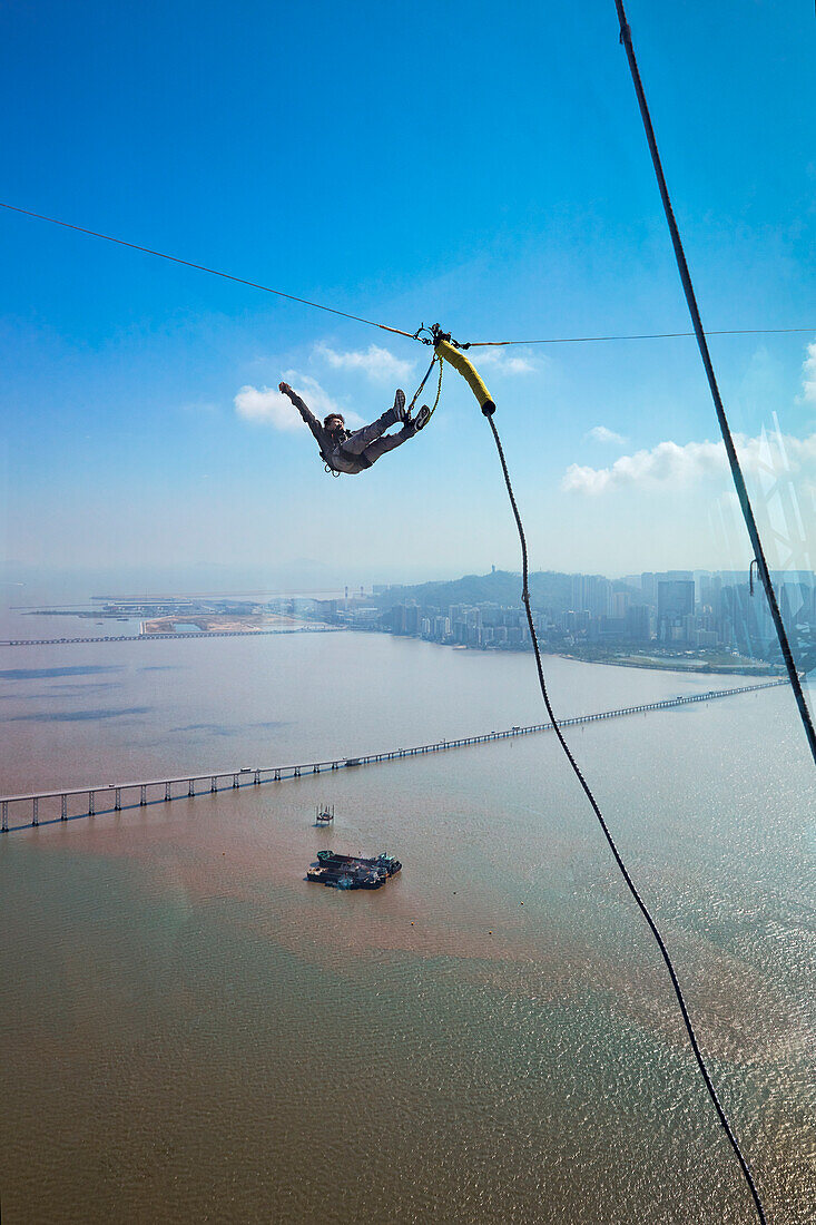  Ein Mann macht einen Bungee-Sprung vom Macau Tower, der über die höchste (233 m) kommerzielle Bungee-Jumping-Plattform der Welt verfügt. Macau, China. 