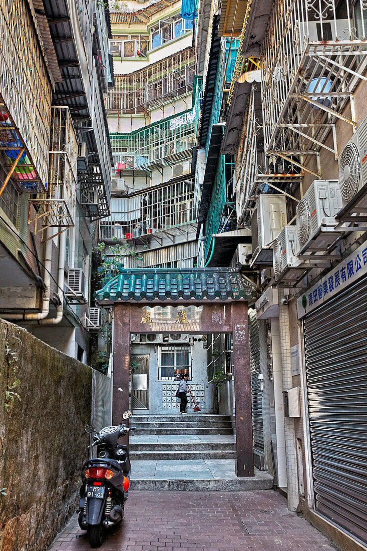  Eine schmale Gasse zwischen mehrstöckigen Wohnhäusern mit eingezäunten Balkonen. Macau, China. 