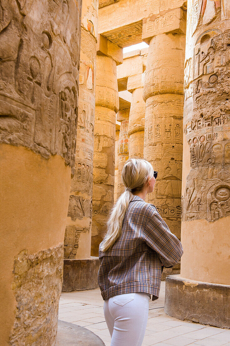 Junge Frau in der großen Hypostylhalle im Bezirk Amon-Re, Karnak-Tempel-Komplex, Luxor, Ägypten, Nordostafrika