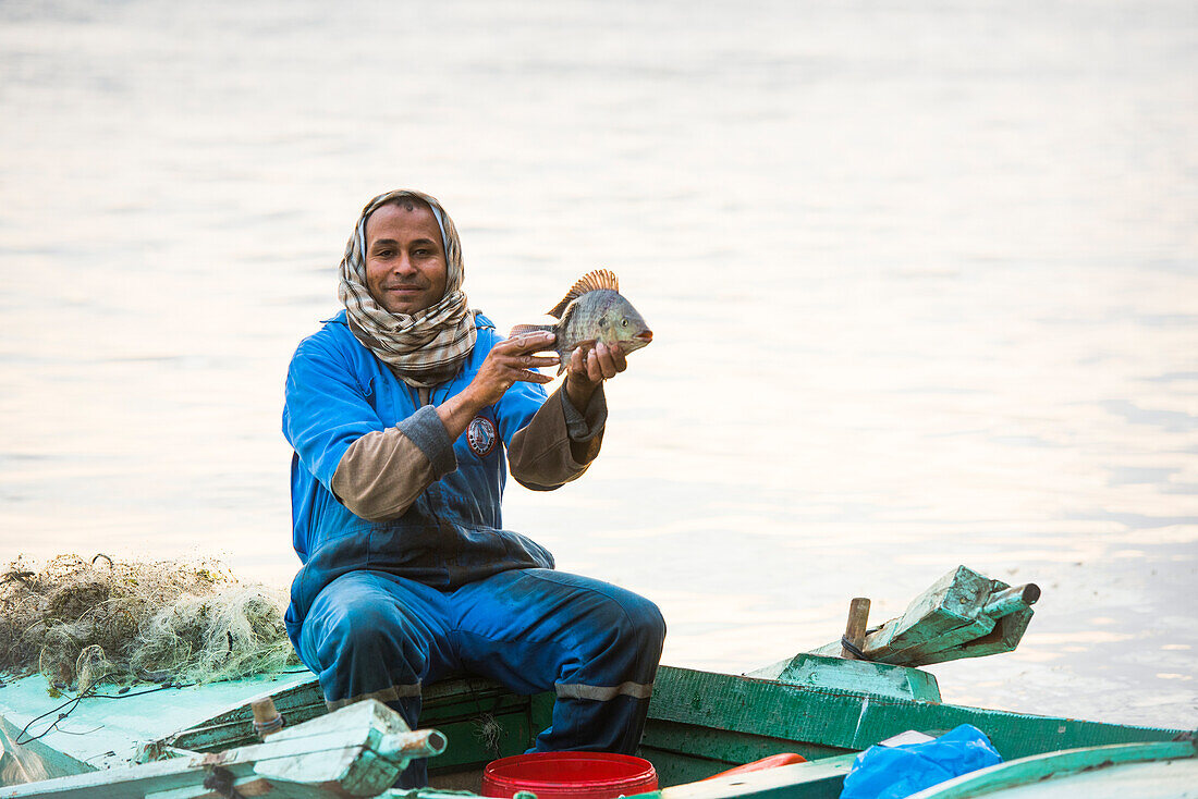 Fischer in einem Boot zeigt eine Dorade, Ufer des Nils in der Nähe von Esna, Oberägypten, Ägypten, Nordostafrika