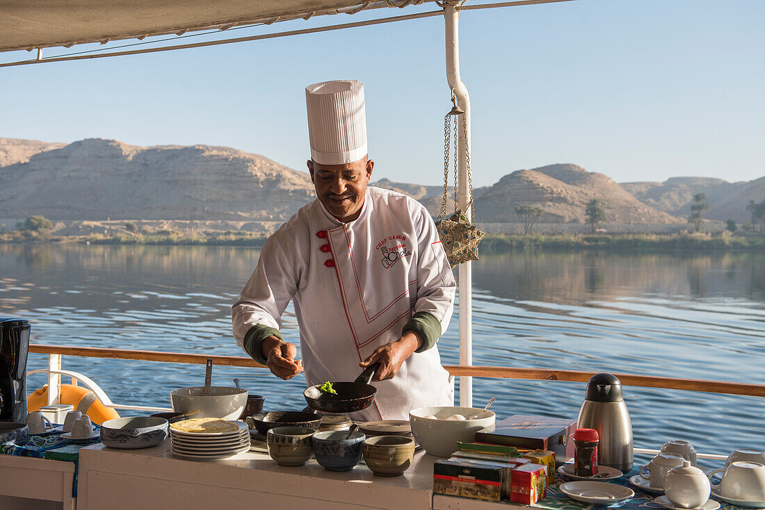 Chef preparing breakfast pancakes  on the upper deck of the dahabeah,passenger river boat of the Lazuli fleet, sailing on the Nile river, Egypt, northeast Africa