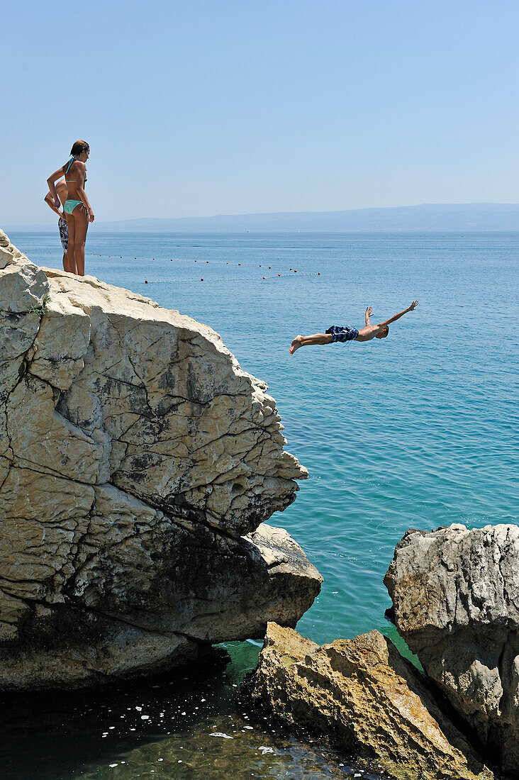 Jugendliche springen von Felsen ins Meer, beim Strand Jezinac am Fuße des Hügels Marjane, Split, Dalmatien, Kroatien, Südosteuropa