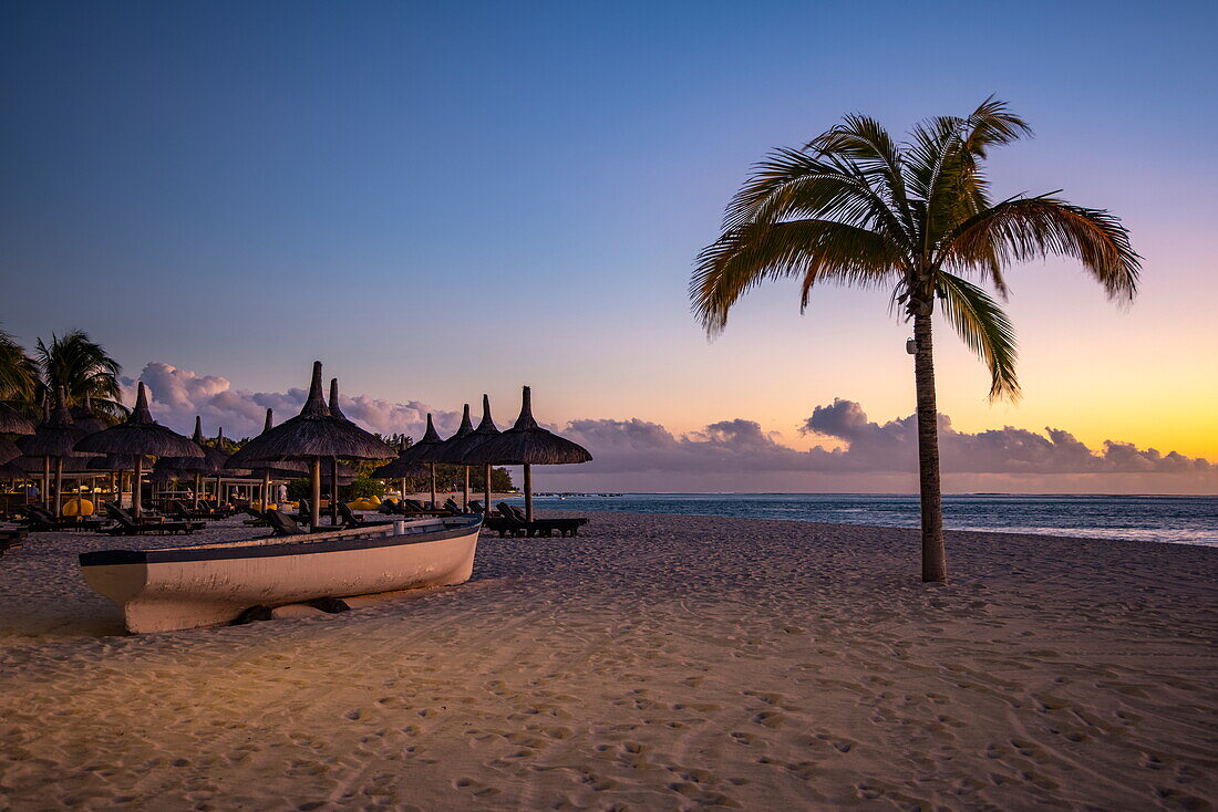  Fishing boat, thatched umbrellas and coconut trees on the beach of Dinarobin Beachcomber Golf Resort 