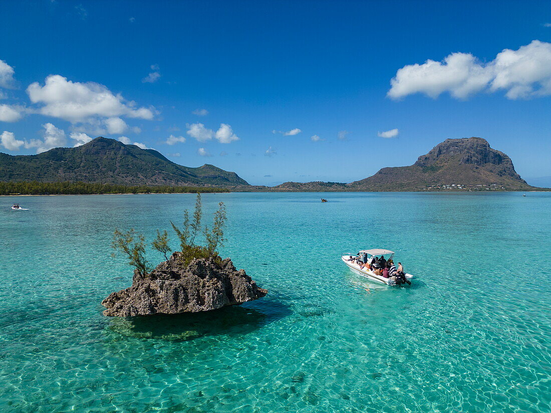  Aerial view of a tour boat in a lagoon next to a rocky island with coastline and Le Morne mountain in the distance, Le Morne, Rivière Noire, Mauritius, Indian Ocean 