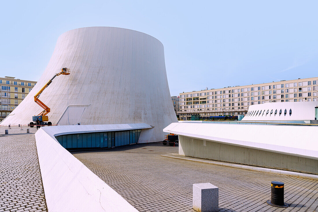  Cultural centre Espace Oscar Niemeyer with ›Grand Volcan‹ (Big Volcano) and ›Petit Volcan‹ (Small Volcano) and lifting platform for cleaning the wall paint and view of houses by Auguste Perret in Le Havre on the Alabaster Coast (Côte d&#39;Albatre, Cote d&#39;Albatre) in the Seine-Maritime department in the Normandy region of France 