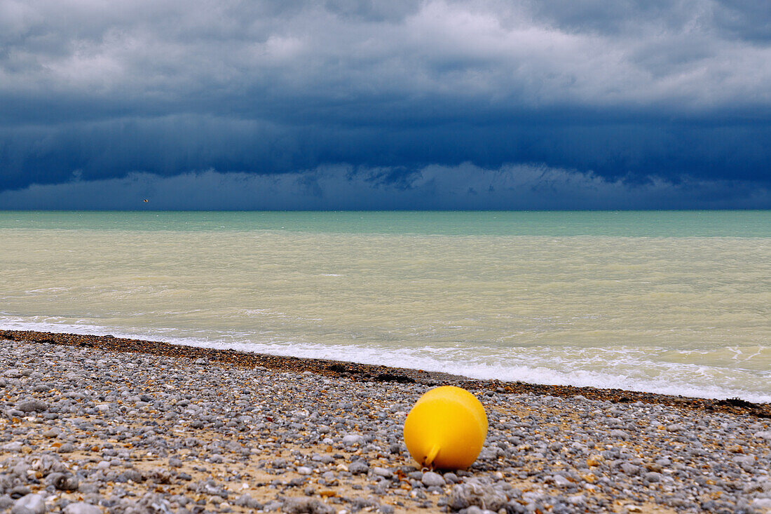  Storm clouds over the sea on the pebble beach with yellow buoy at low tide in Dieppe on the Alabaster Coast (Côte d&#39;Albâtre, Cote d&#39;Albatre) in the Seine-Maritime department in the Normandy region of France 