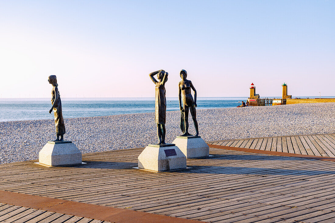 Bronzestatuen von drei Mädchen unter dem Titel "L'heure du bain" von Dominique Denry am Strand und Blick auf die Hafeneinfahrt bei Sonnenuntergang in Fécamp (Fecamp) an der Alabasterküste (Côte d'Albâtre, Cote d'Albatre) im Département Seine-Maritime in der Region Normandie in Frankreich