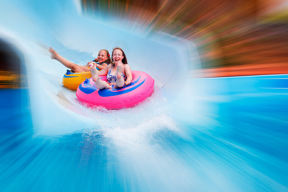  Radiale Unschärfe von Mutter und Tochter, die gemeinsam im Wasser gleiten, im Acqua Plus Water Park. Kreta, Griechenland. 