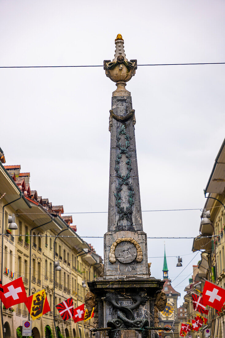 Altstadt, alte Gebäude und Flaggen und Brunnen an einem regnerischen Tag in der Stadt Bern, Kanton Bern, Schweiz.