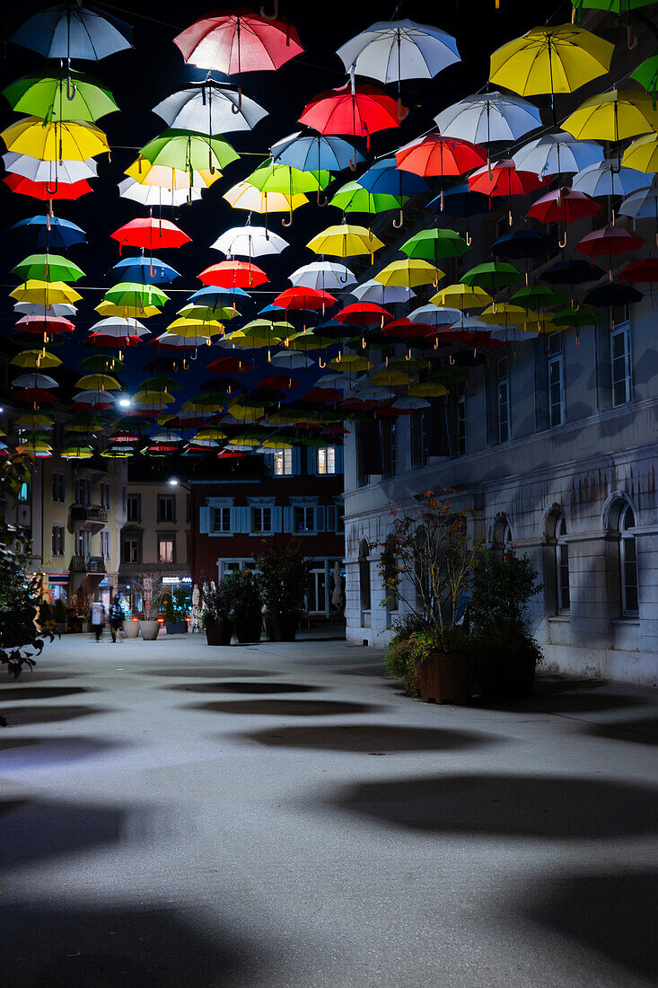 Beautiful Old Town with Illuminated Colorful Hanging Umbrellas with Shadow on the City Street at Night in Olten, canton Solothurn, Switzerland.