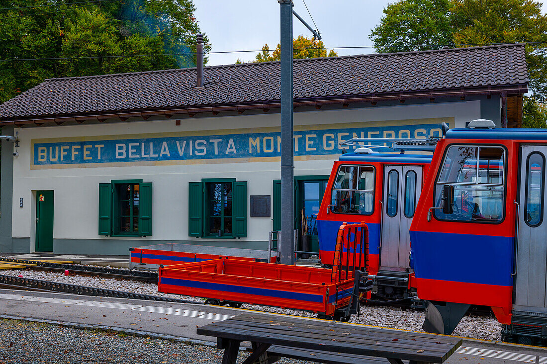  Bergbahn im Bahnhof mit Gleisen und Restaurant Bella Vista an einem Herbsttag in Monte Generoso, Tessin, Schweiz. 