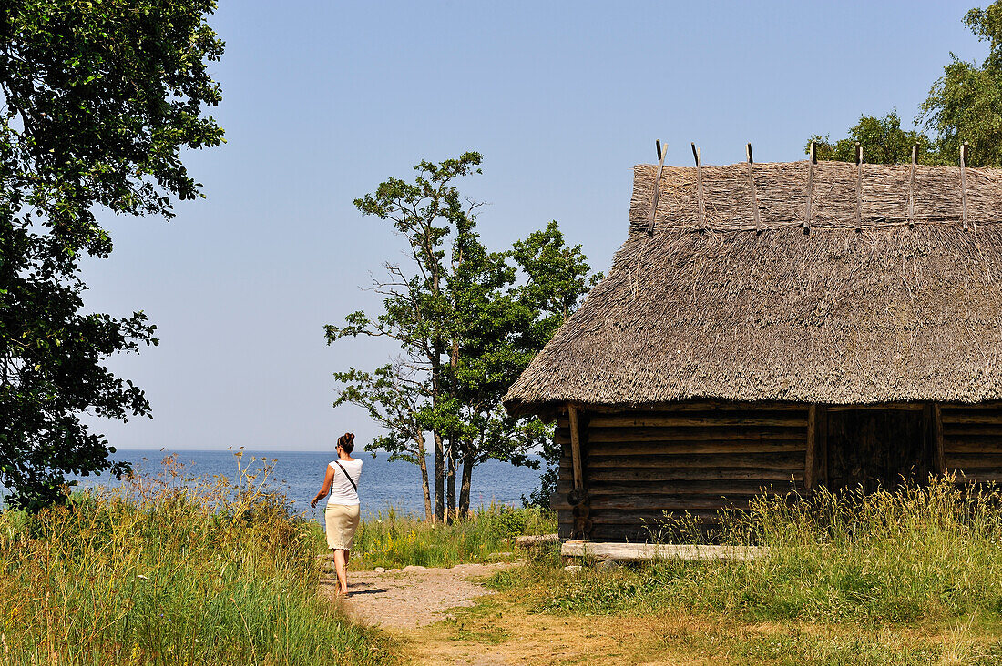  Frau zu Fuß an der Küste neben einer Fischerhütte, Altja, Ostseeküste, Lahemaa Nationalpark, Estland, Nordeuropa 