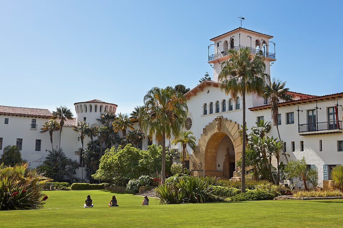 People sit on a manicured green lawn in front of the Santa Barbara County Courthouse. Santa Barbara, California, USA.