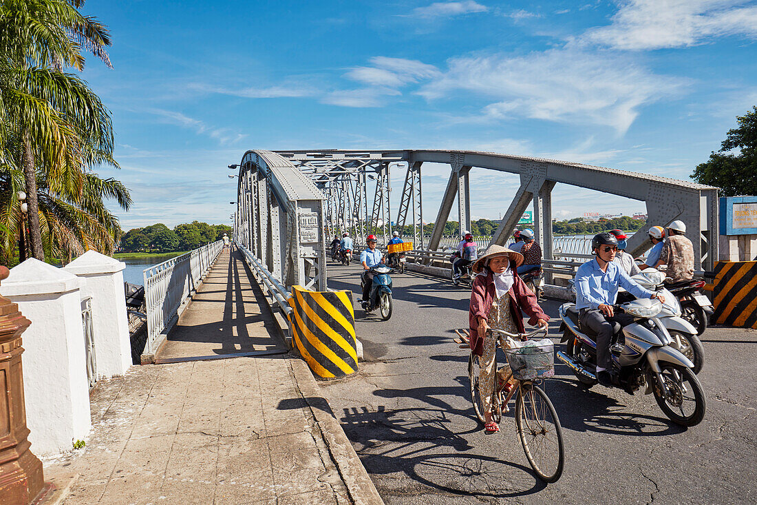 People on bikes ride on Truong Tien Bridge. Hue, Vietnam.