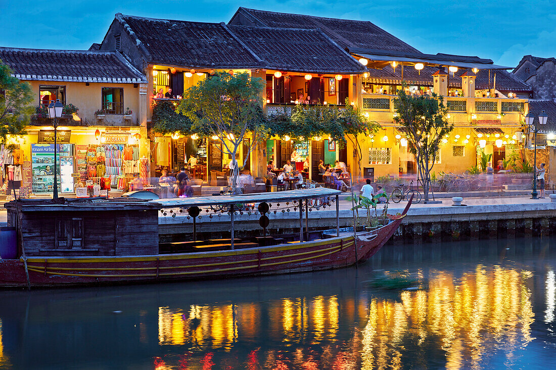 Old houses along the Thu Bon River in Hoi An Ancient Town illuminated at dusk. Hoi An, Quang Nam Province, Vietnam.