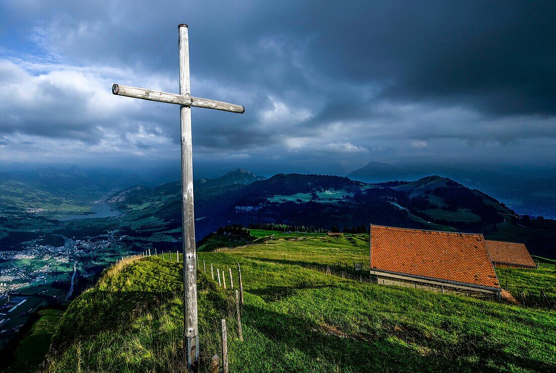  Evening mood on the Rigi under a cloudy sky with summit cross and alpine huts, view of Lauerz and Lake Lauerz, Canton Lucerne, Switzerland 