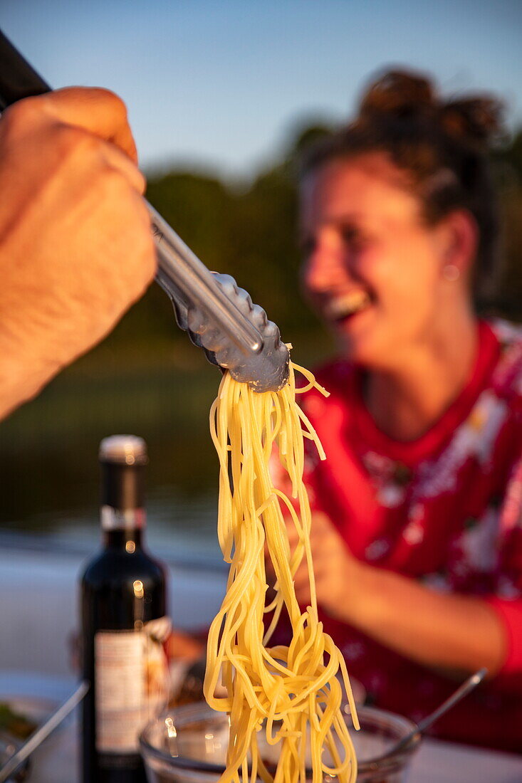 Detail von Spaghetti, serviert auf Deck von Hausboot, mit lachender Frau im Hintergrund, Wineport, in der Nähe von Glasson, County Westmeath, Irland, Europa