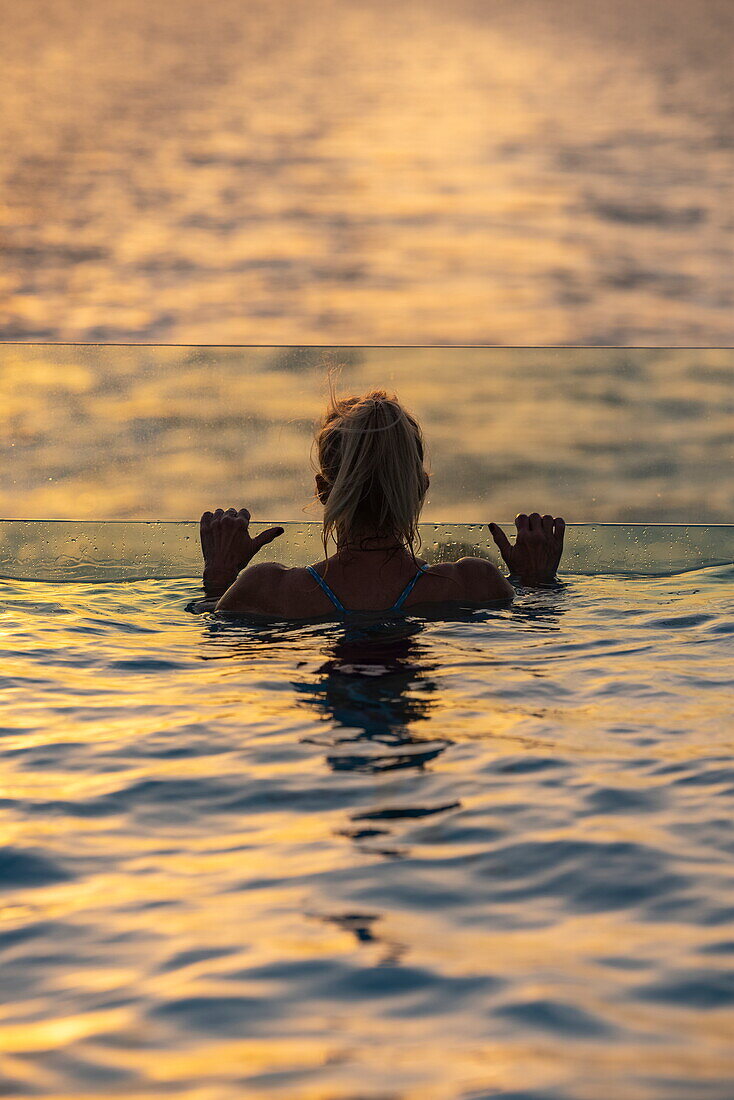 Silhouette einer Frau in Infinity-Pool auf dem Achterdeck des Expeditionskreuzfahrtschiffs SH Diana (Swan Hellenic) bei Sonnenuntergang auf hoher See, in der Nähe von Jemen, Nahen Osten