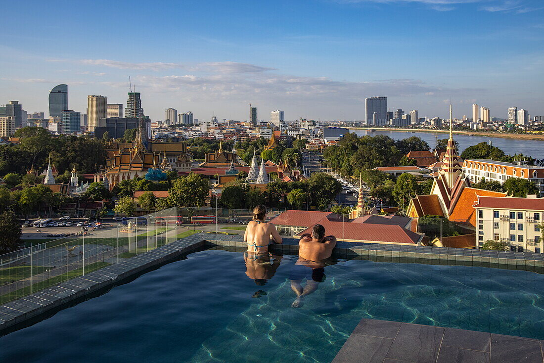 Paar im Infinity-Pool auf dem Dach des Glow Park Hotels mit Blick auf den Königspalast und die Skyline der Stadt, Phnom Penh, Phnom Penh, Kambodscha, Asien