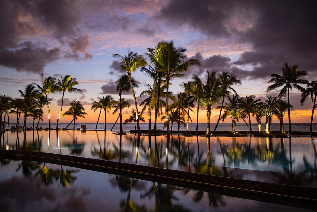 Spiegelung von Kokospalmen im Swimmingpool des Trou aux Biches Beachcomber Golf Resort & Spa bei Sonnenuntergang, Trou aux Biches, Pamplemousses, Mauritius, Indischer Ozean