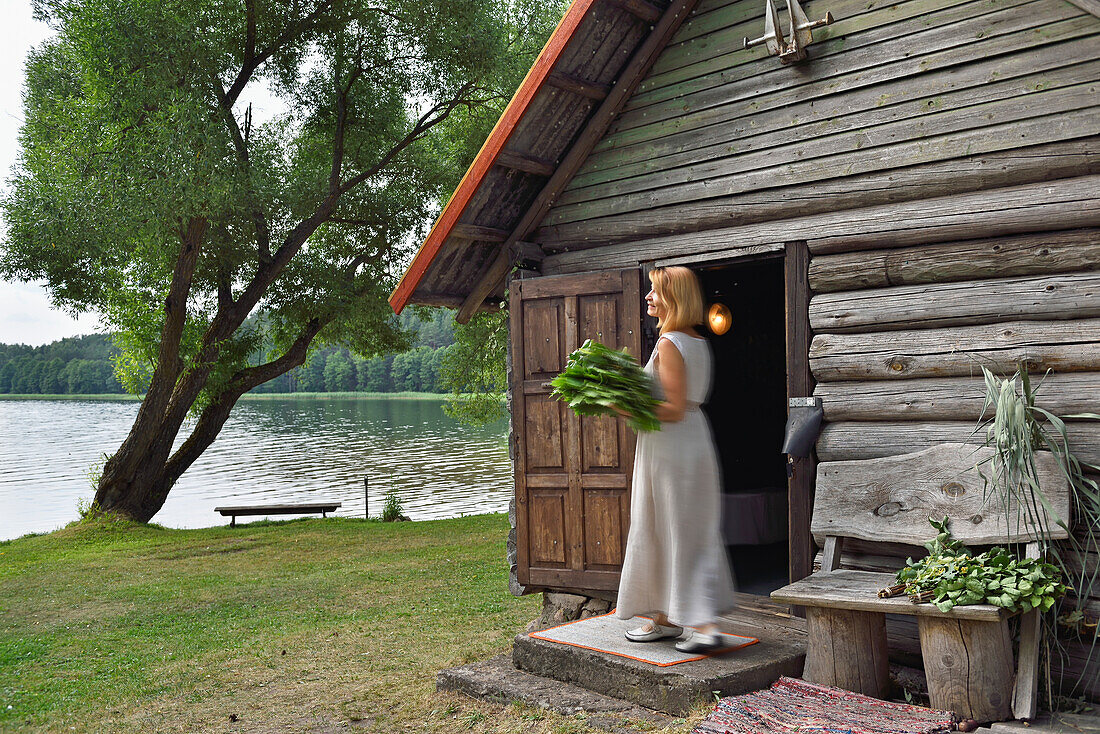 Frau trägt Lindenzweige für die traditionelle Sauna am Lusiai-See in Paluse, Aukstaitija-Nationalpark, Litauen, Europa