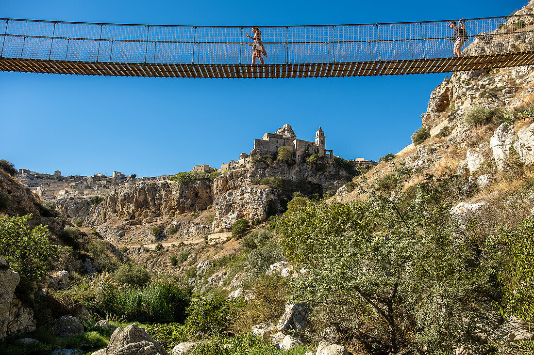 Menschen überqueren die Brücke im Park Murgia Materana (Parco della Murgia Materana), Matera, Basilikata, Italien.