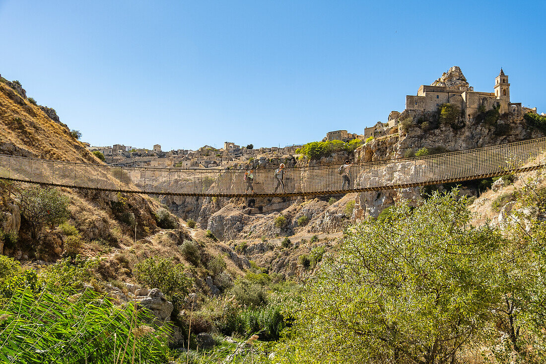 People crossing the bridge of the Murgia Materana park (Parco della Murgia Materana), Matera, Basilicata, Italy.