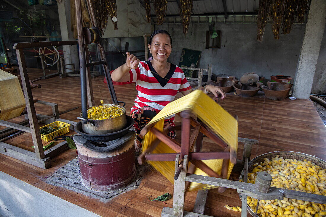 Frau spinnt Seide aus den Kokons goldener Seidenraupen, Kunsthandwerksfabrik 'Silk Island', Koh Oknha Tei, Khsach Kandal District, Provinz Kandal, Kambodscha, Asien